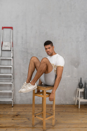 Man sitting on chair with legs raised and knees bent