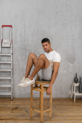 Homme assis sur une chaise avec les jambes levées et les genoux pliés