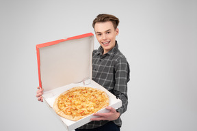 Beau jeune homme tenant une pizza