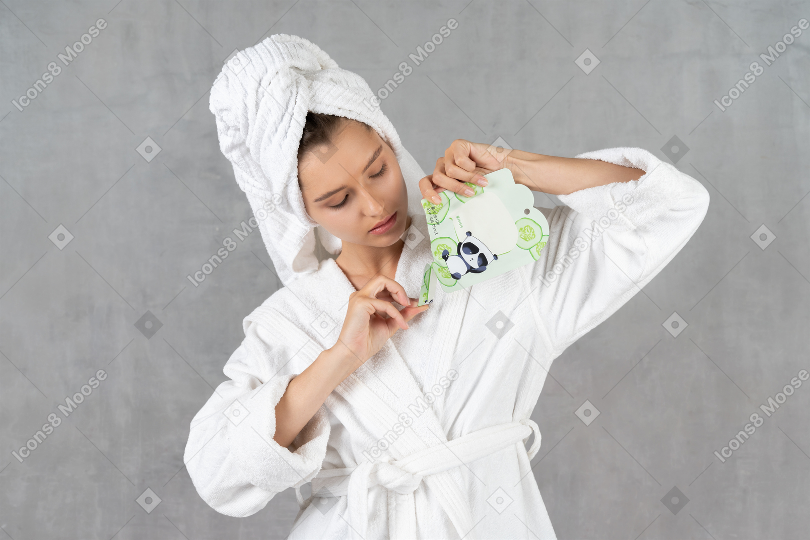 Frau im bademantel, die eine blattmaskenpackung öffnet