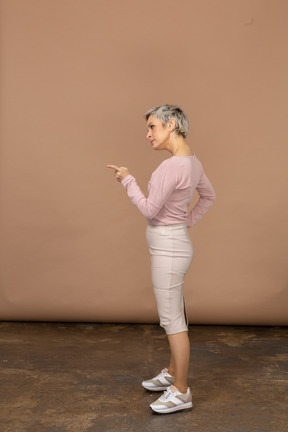Vista lateral de uma mulher com roupas casuais apontando com o dedo