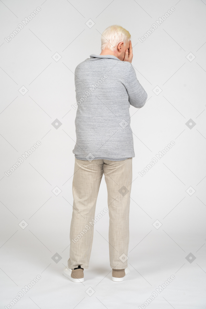 Back view of man covering his face with both hands