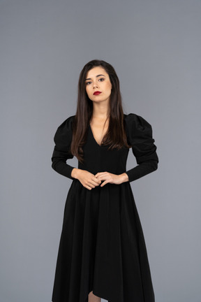 Front view of a young lady in a black dress standing still