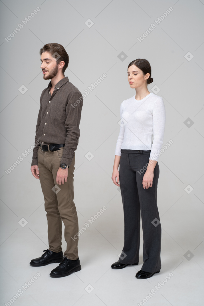 Three-quarter view of a young couple in office clothing standing still with her eyes closed