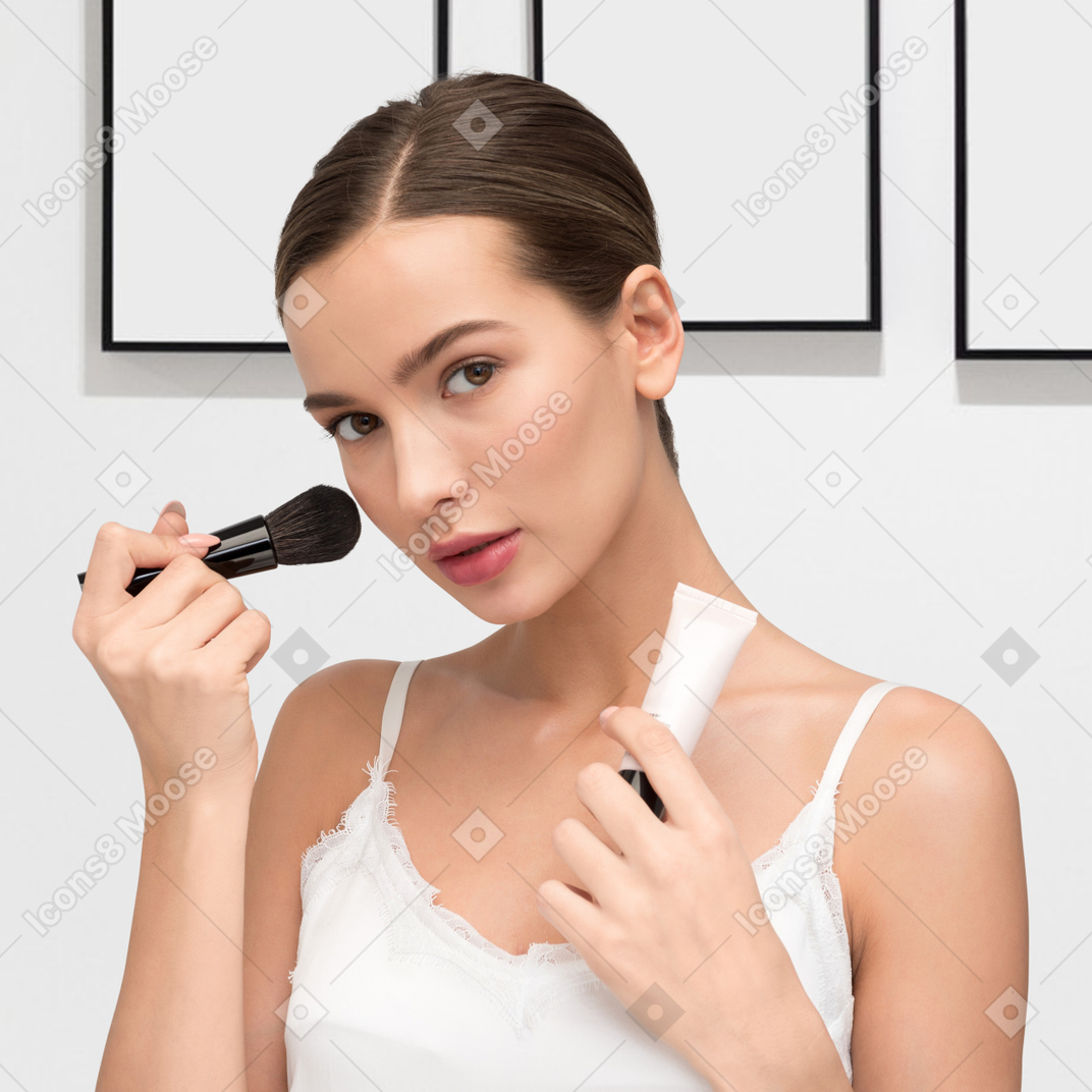 A woman holding a makeup brush in her hand