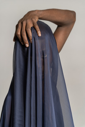 Front view of a young afro man covered with a dark blue shawl touching his head