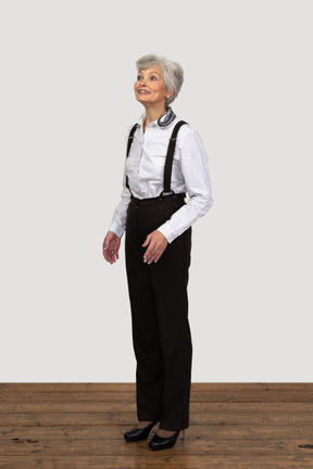 Vista de tres cuartos de una mujer anciana esperanzada vestida con ropa de oficina
