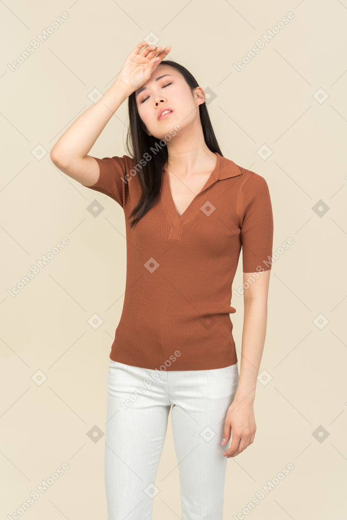 Looking tired young asian woman touching head