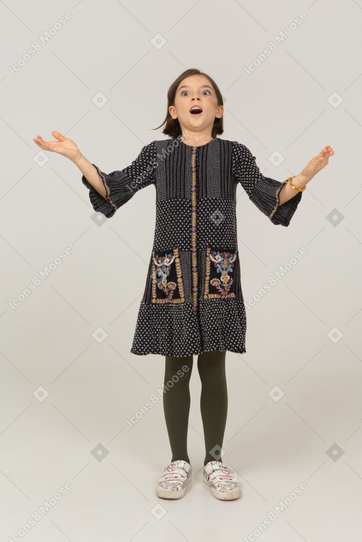 Front view of a surprised little girl in dress outspreading arms
