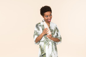 Young black short haired woman in a dressing gown, holding a reusable bottle