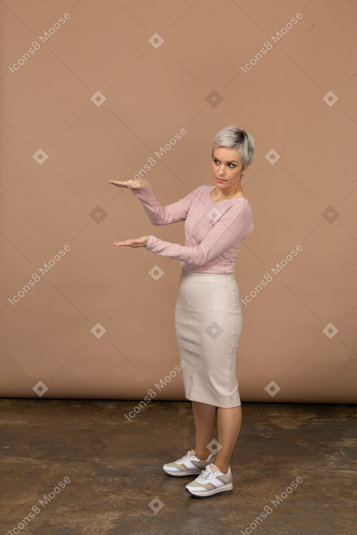 Vista laterale di una donna in abiti casual che mostra le dimensioni di qualcosa