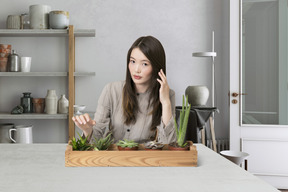 A woman sitting at a table with succulents in front of her