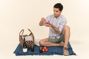 ピクニックを持っていると果物を食べる若い白人男