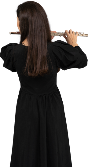 Vue noire d'une jeune femme en robe noire jouant de la flûte