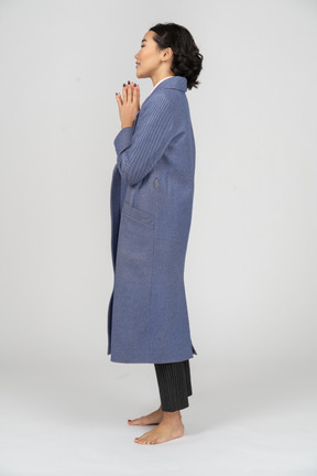 Side view of a woman in blue coat with hands folded