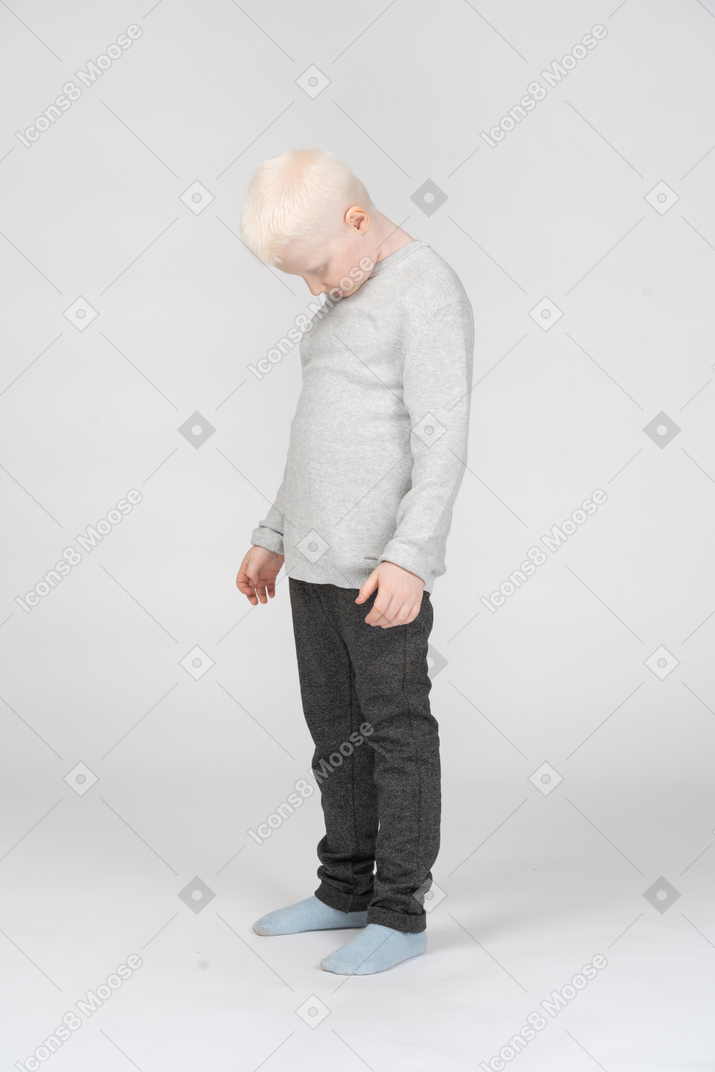 Little boy standing with his head down