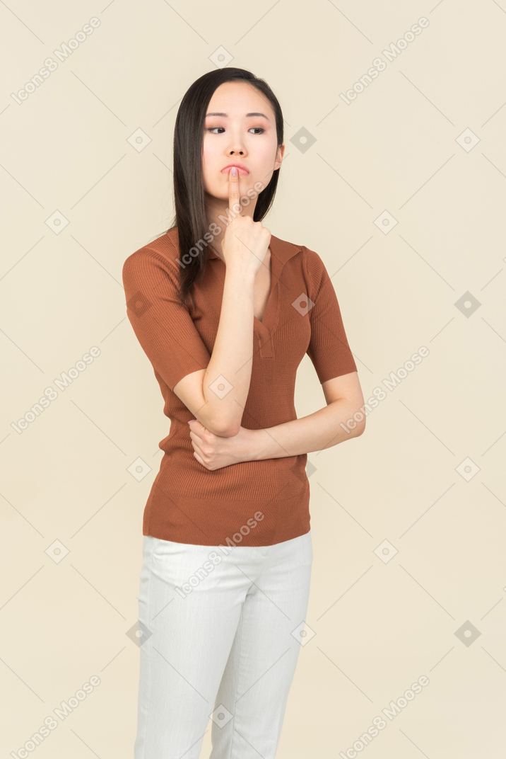 손가락으로 턱을 만지고 잠겨있는 젊은 아시아 여자
