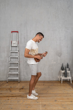 Seitenansicht eines mannes, der aufgeregt ukulele spielt
