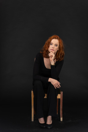 A frontal view of the cute girl sitting on the wooden chair