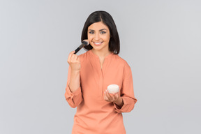 Femme indienne appliquant la poudre pour le visage sur son visage