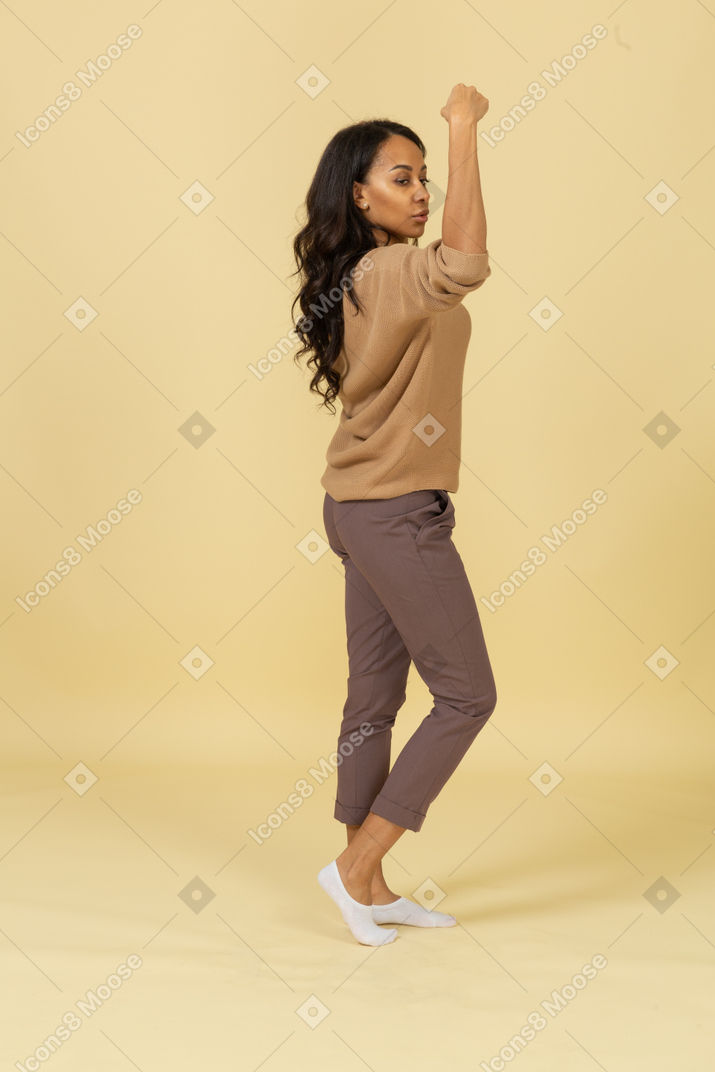 Side view of a dark-skinned young female raising hands and clenching fists