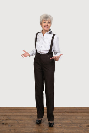 Vue de face d'une vieille dame souriante gesticulant en tenue de bureau