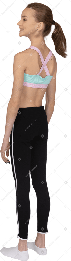 Dreiviertel-rückansicht eines jugendlichen mädchens in der sportbekleidung, die beiseite schaut und lächelt