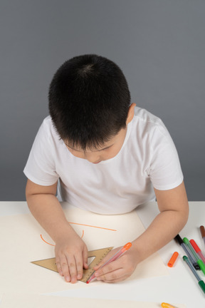 Asian boy drawing geometric shapes using triangular ruler