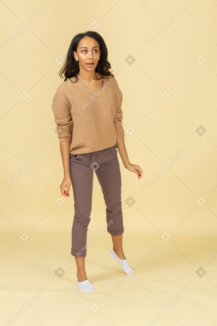 Vista frontale di una giovane donna dalla pelle scura curiosa che si appoggia sulla sua gamba