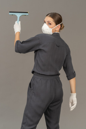 Vista traseira de uma mulher olhando por cima do ombro durante a limpeza