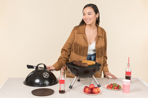 Jovem mulher asiática fazendo churrasco