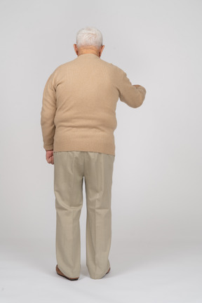 Vista traseira de um velho em roupas casuais, apontando para baixo