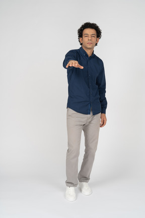 Front view of a man in casual clothes pointing with hand