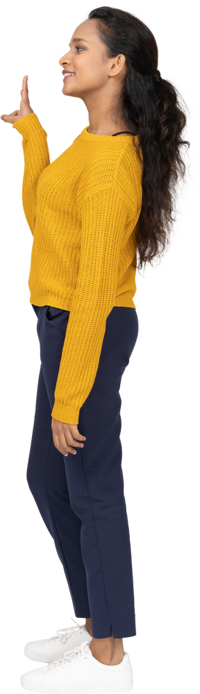 Vista lateral de una niña feliz en ropa casual que muestra el signo v