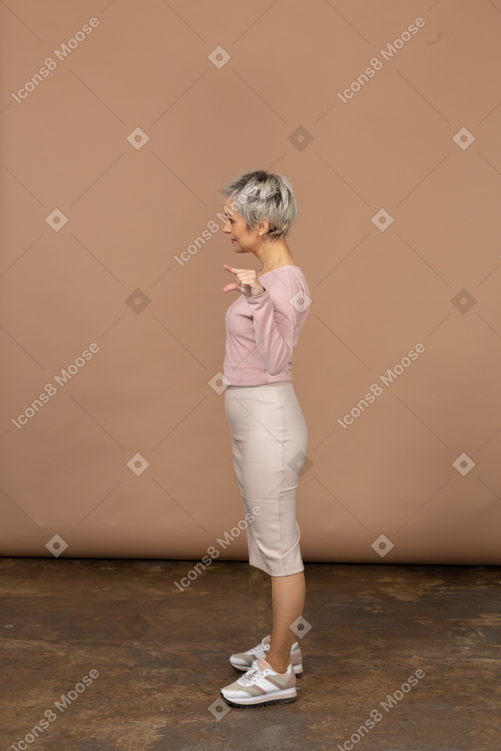 Vue latérale d'une femme heureuse dans des vêtements décontractés montrant la petite taille de quelque chose