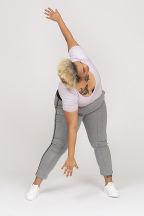 Mujer inclinada hacia adelante y haciendo abdominales laterales con los brazos extendidos