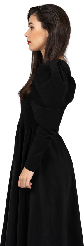 Vista laterale di una giovane donna in un abito nero in piedi ancora