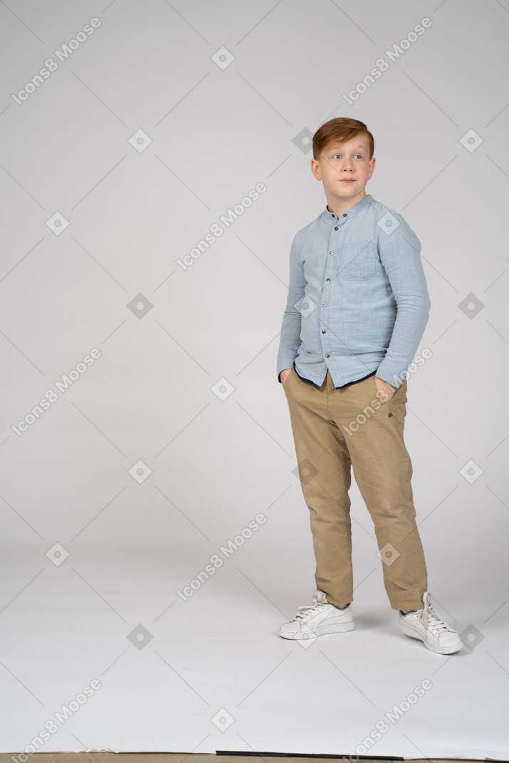 Мальчик стоит с руками в карманах