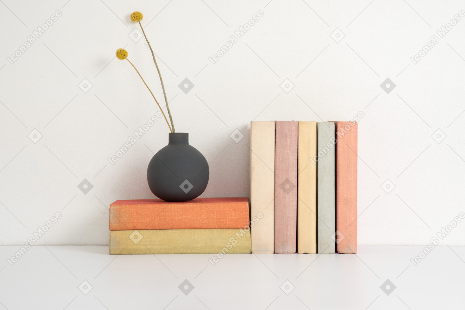 Ceramic vase with dried flowers on a stack of books