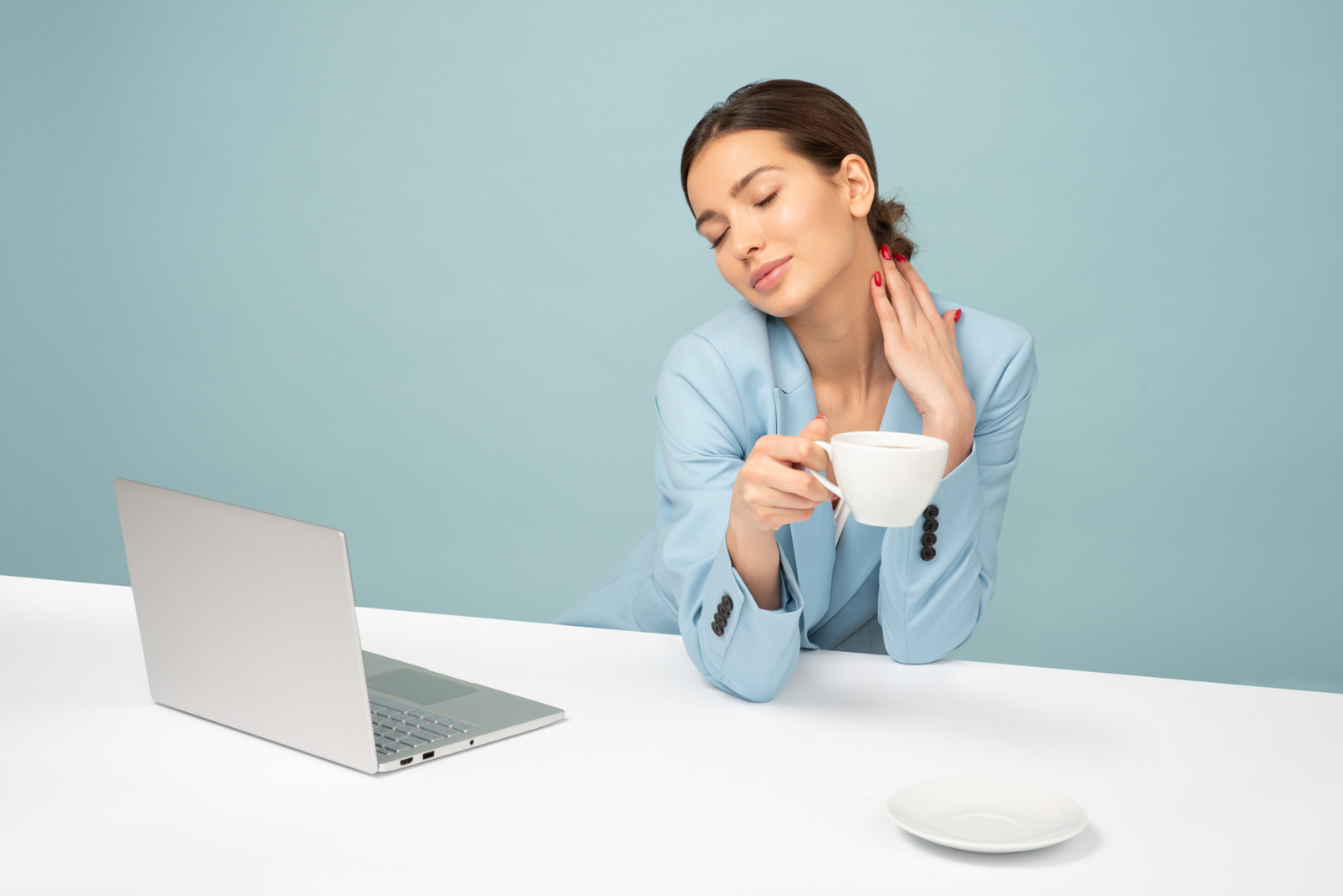 Young attractive employee holding a cup of coffee and touching her neck