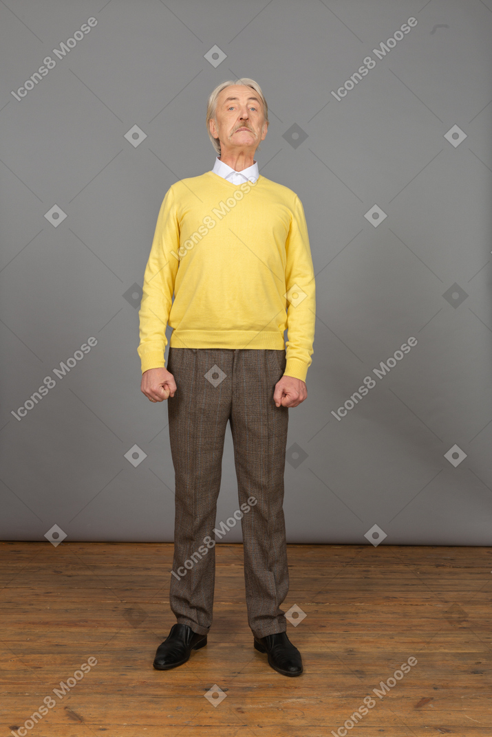 頭を上げてカメラを見ている黄色のプルオーバーで好奇心旺盛な老人の正面図