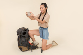 Jovem mulher asiática em pé perto de mochila e tirar fotos