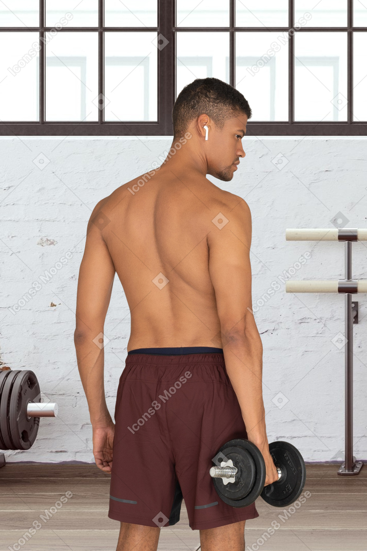 A man with no shirt is holding a dumbbell