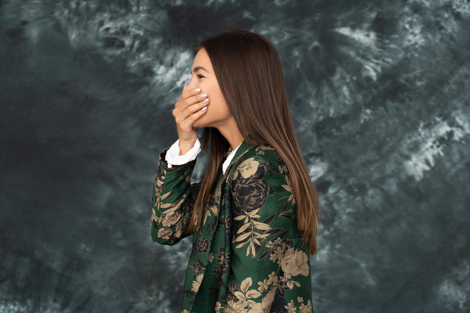 Side photo of young female in green japanese jacket hides her mouth