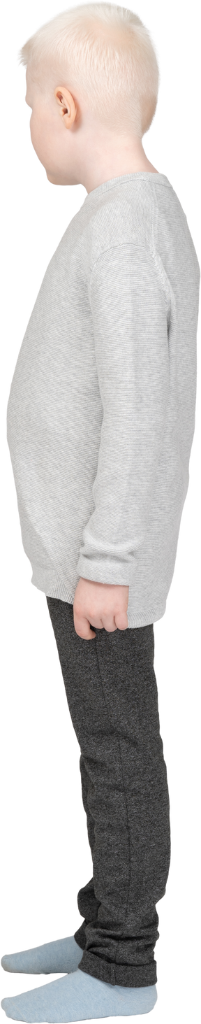 Vista lateral de un niño rubio en ropa casual de pie todavía