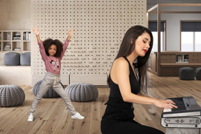 Woman playing synthesizer and child dancing