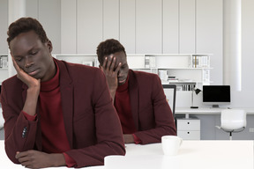 Two frustrated men sitting at table with cups of coffee