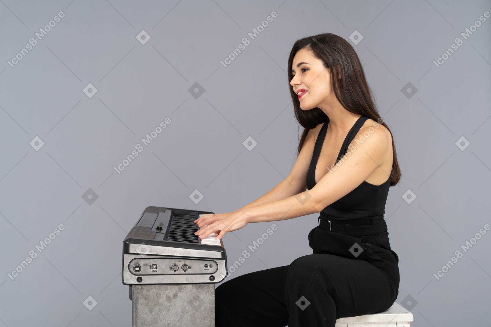 피아노를 연주하는 동안 검은 양복에 웃는 앉아 젊은 아가씨의 측면보기