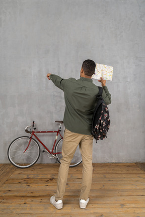 Back view of a man with a backpack and a map showing directions