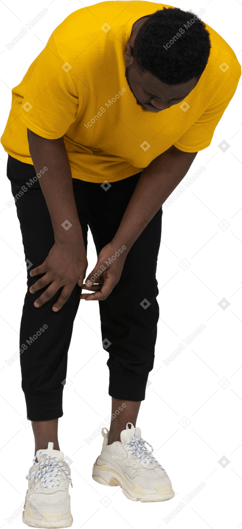 Front view of a dark-skinned man in yellow t-shirt touching his knee